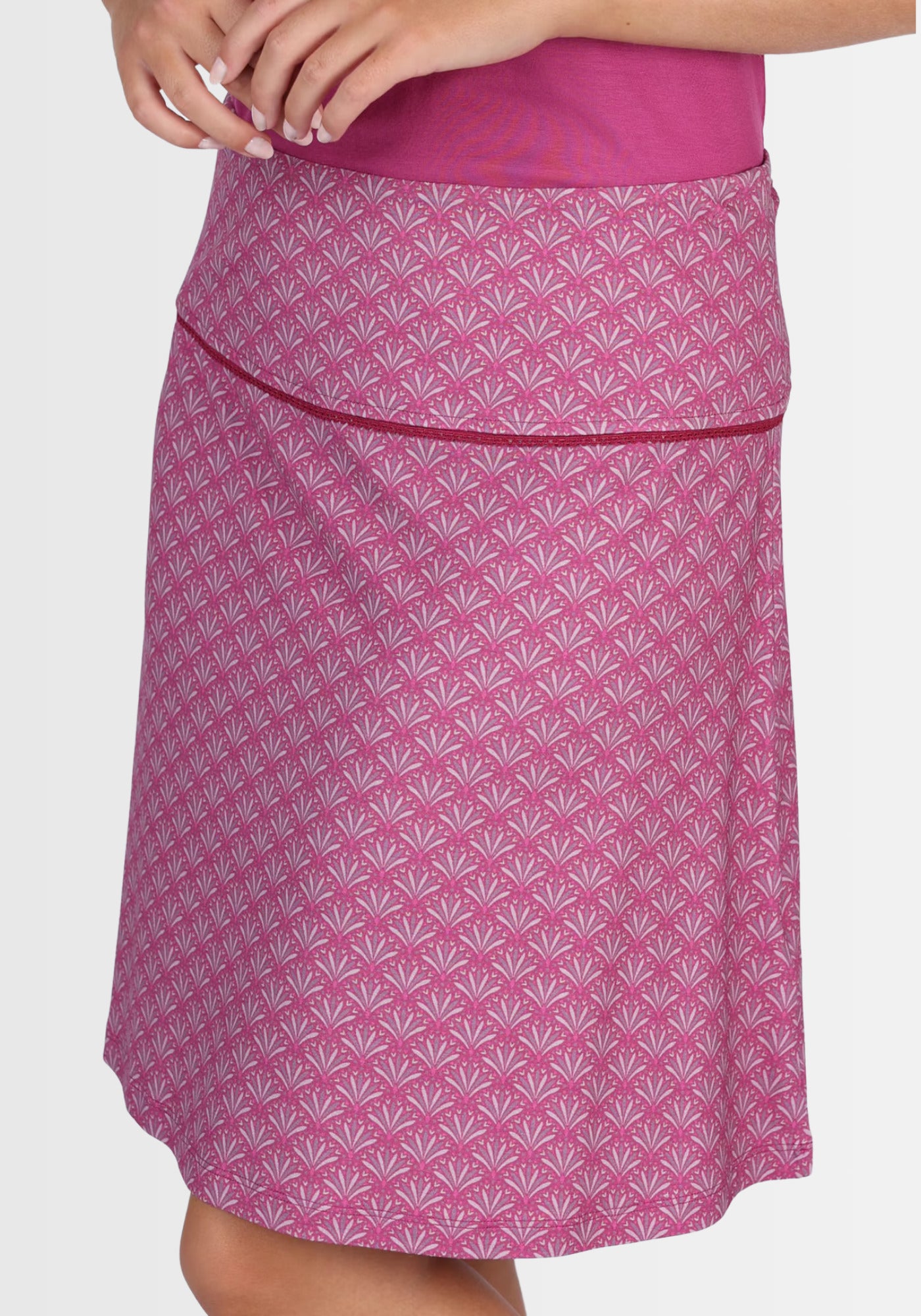 Nahaufnahme des breiten Bündchens am Rock „Amanda“ in Raspberry, verziert mit einer zarten Spitzenkante. Dieser liebevolle Akzent rundet das Design in frischem Federprint geschmackvoll ab.