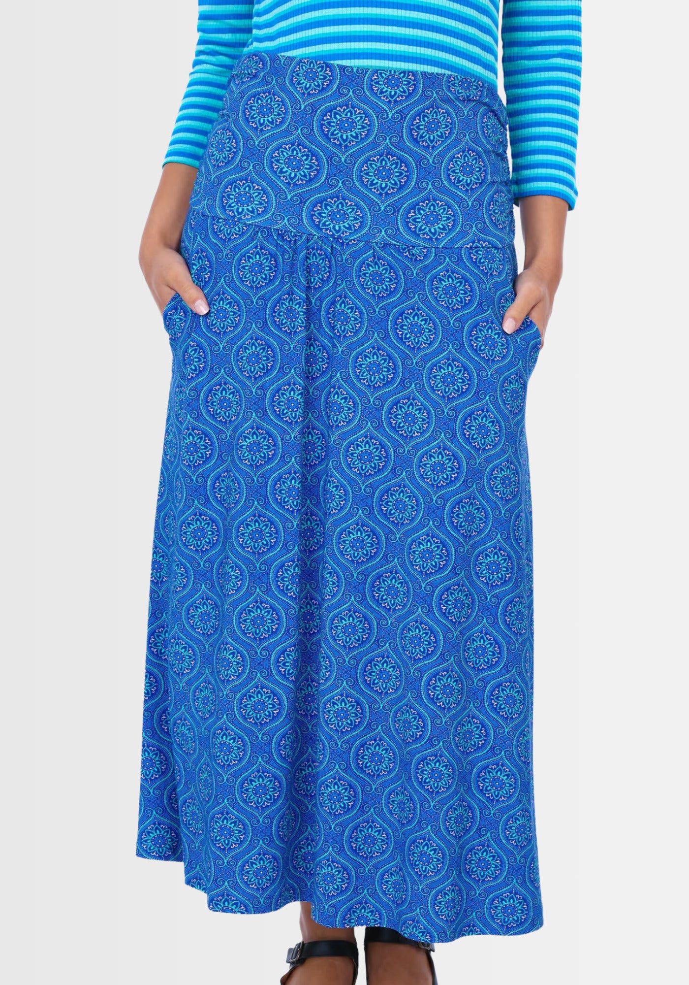 Ein Model trägt den Rock „Kalla“ in Lapiston, verziert mit einem verspielten Mandala-Druck. Der umschlagbare Bund und die leichte A-Linie umschmeicheln die Figur und verleihen dem Outfit einen femininen Touch.