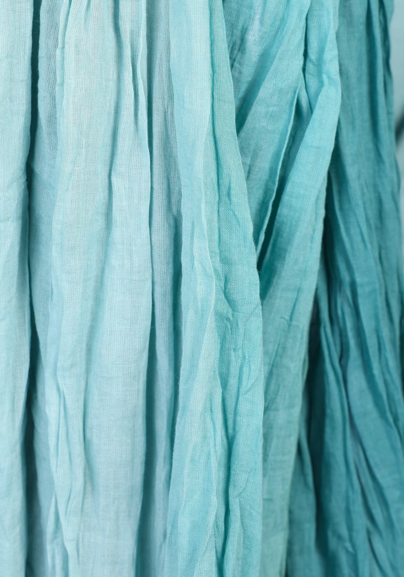 Nahaufnahme des kunstvollen Musters des Tuchs „Asta – Mermaid“. Die fein strukturierte Baumwolle zeigt einen harmonischen Farbverlauf, der an die schimmernden Töne einer Meerjungfrau erinnert.