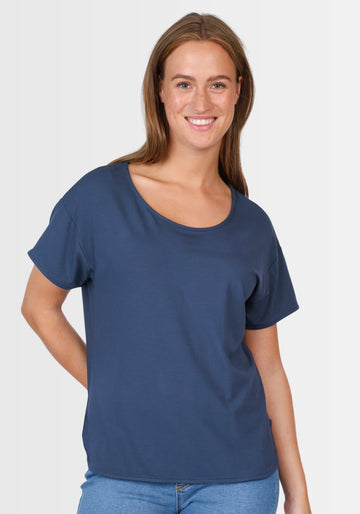 Frau lächelt in die Kamera und präsentiert das locker geschnittene T-Shirt „Betzi“ in Dunkelblau, das sich perfekt für jeden Tag eignet.