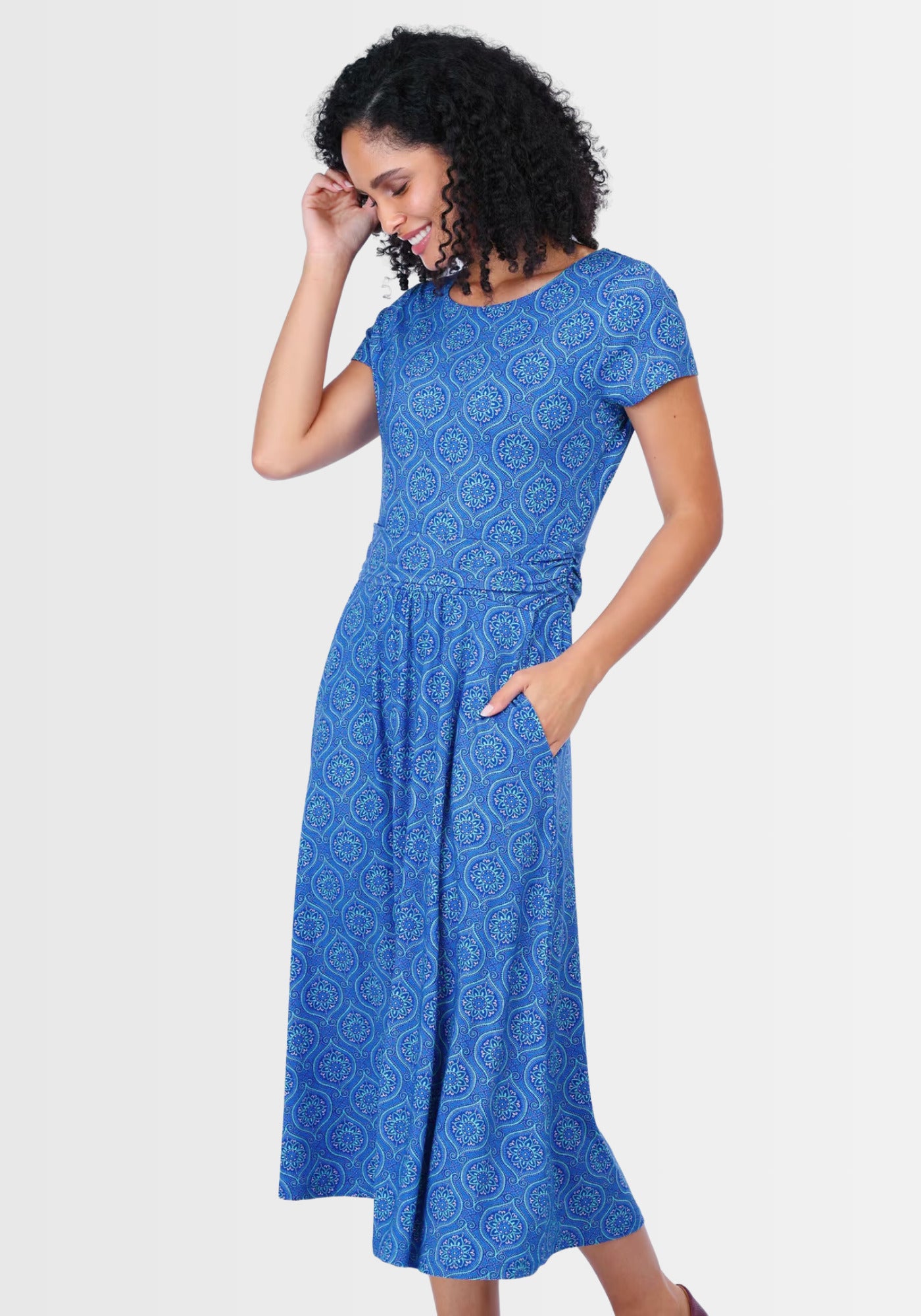 Lifestyle-Aufnahme des „Malind mandala“ Kleids in Lapis. Der luftige Schnitt, das ornamentale Muster und die LENZING™ ECOVERO™-Viskose machen es zum perfekten Begleiter für warme Tage und festliche Anlässe.

