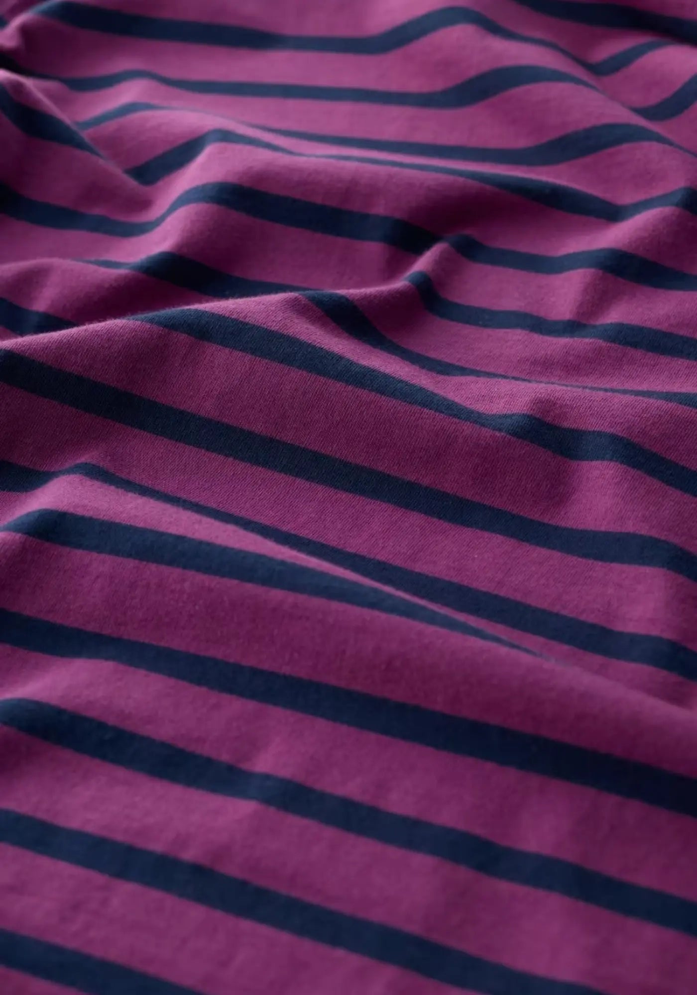 Bequemes Langarmshirt mit Bootsausschnitt und Breton-inspirierten Streifen, gefertigt aus weichem Bio-Baumwolljersey.
