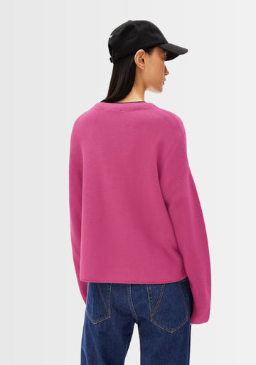Hinteransicht des Merinaa Links Links Pullovers in kräftigem Pink, zeigt die lockere Passform und das verkürzte Design am Rücken.