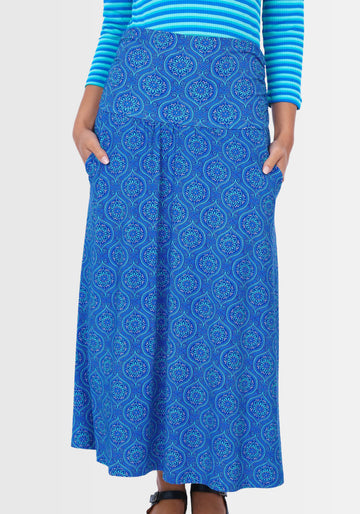 Ein Model trägt den Rock „Kalla“ in Lapiston, verziert mit einem verspielten Mandala-Druck. Der umschlagbare Bund und die leichte A-Linie umschmeicheln die Figur und verleihen dem Outfit einen femininen Touch.

