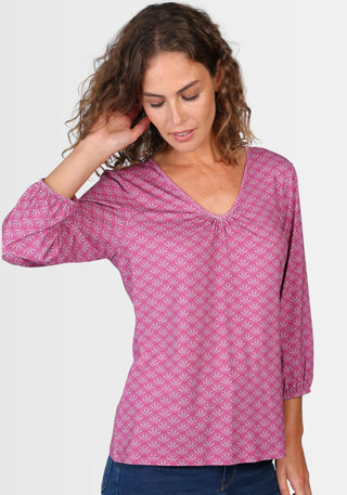 Lifestyle-Aufnahme des Shirts „Andria“ in sattem Himbeerrot, kombiniert mit Jeans und Sandalen. Der lockere Schnitt, das geraffte Dekolleté und die bequemen 3/4-Ärmel machen es zum perfekten Begleiter für jeden Tag.

