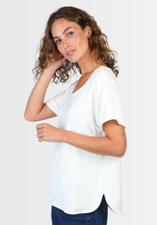 Frau trägt das locker geschnittene T-Shirt „Betzi“ in Ivory von Sorgenfri Sylt, aus LENZING™ ECOVERO™-Viskose und Elasthan, seitlich fotografiert mit lässigem Kurzarm und rundem Halsausschnitt.

