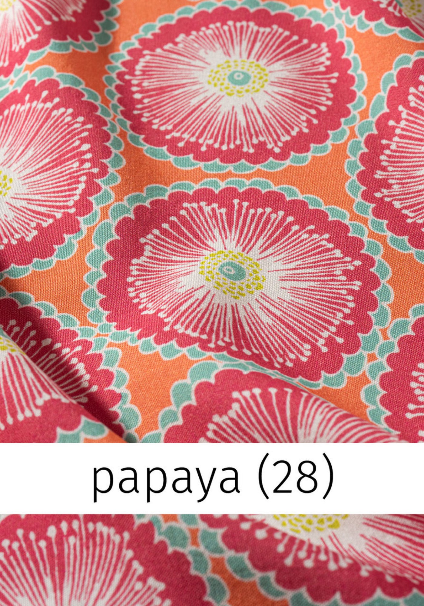Nahaufnahme des einzigartigen, floralen Musters der Tunika "Vivica" in frischen Papaya-Farbtönen, ideal für lebendige Sommerlooks.

